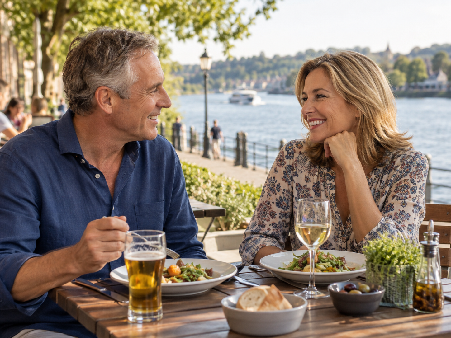 Couple in their 50s enjoying lunch together at a riverside restaurant.